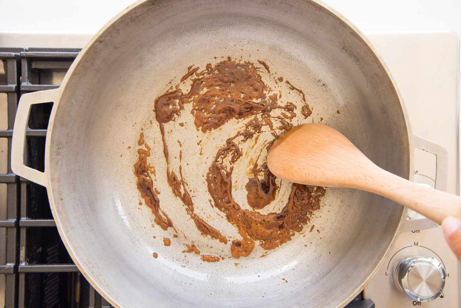 Brown Sugar Stirred Using a Wooden Spoon as It Melts in a Caldero for Pollo Guisado Recipe
