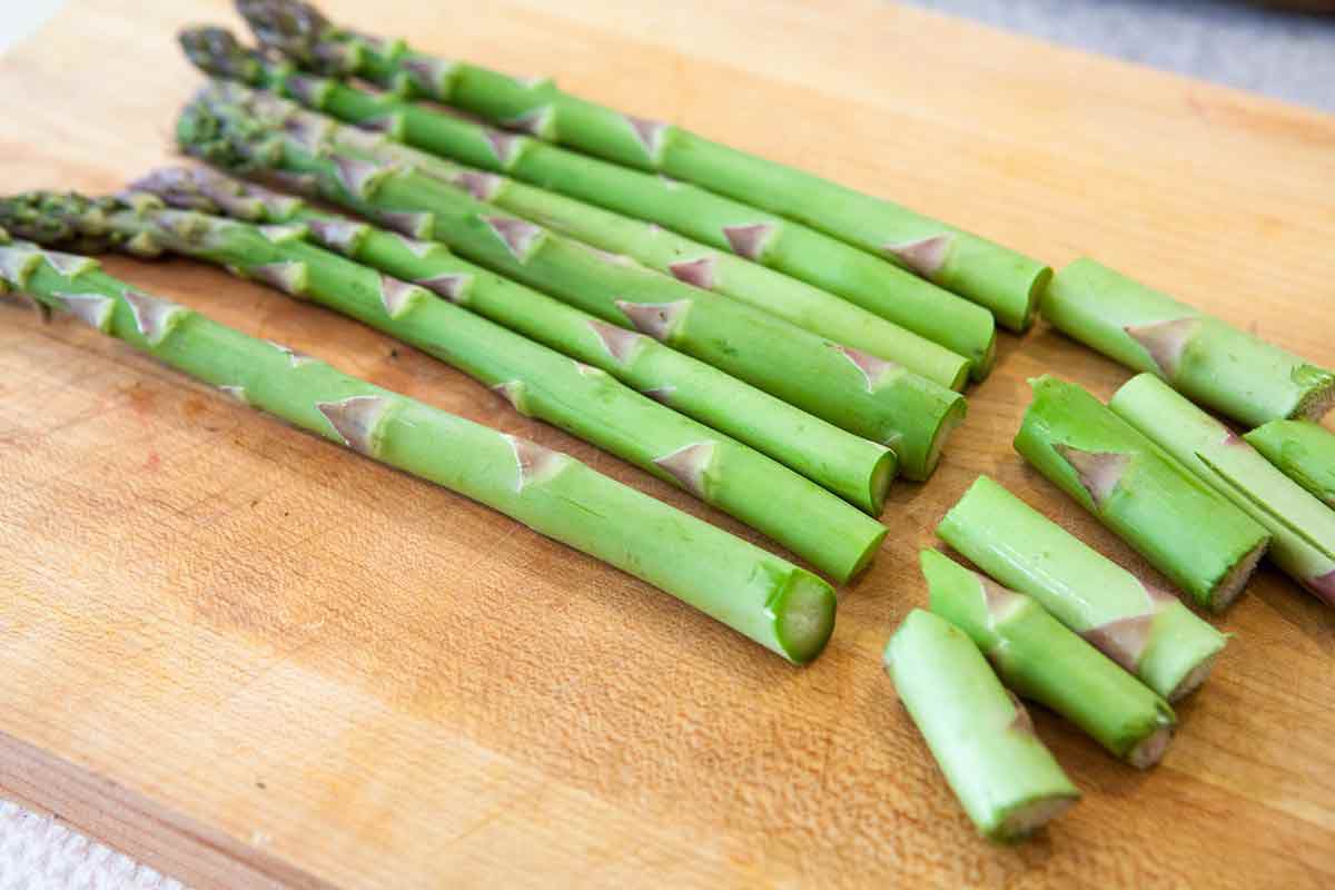 Preparing asparagus spears on cutting board for steamed asparagus