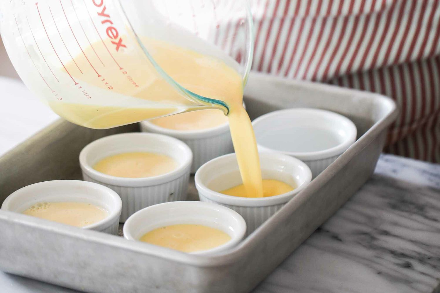 Vanilla Bean Creme Brulee custard being divided between six ramekins