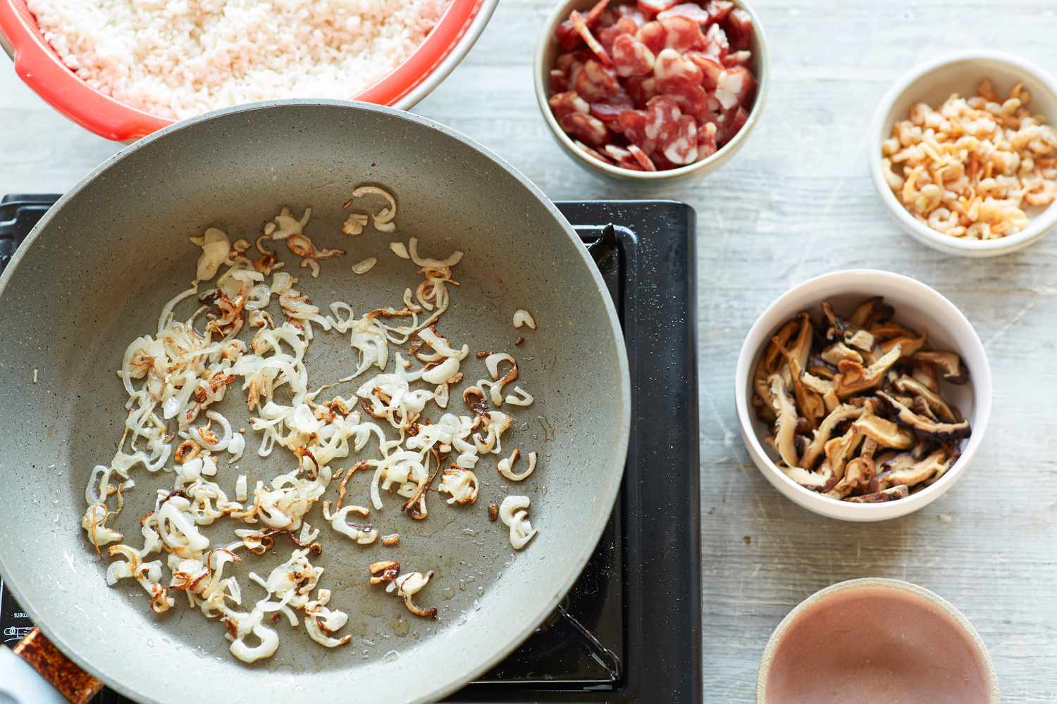 Sauteeing aromatics to make steamed rice with sausage, dried shrimp, and mushrooms