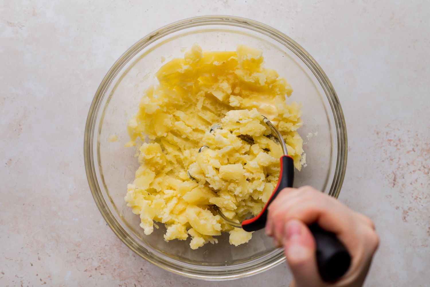 Mashing potatoes in a glass bowl for shepherds pie.