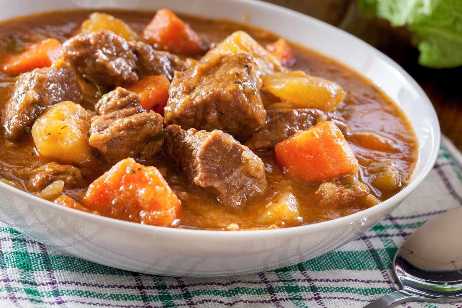 Beef stew with carrots and potatoes in a white bowl