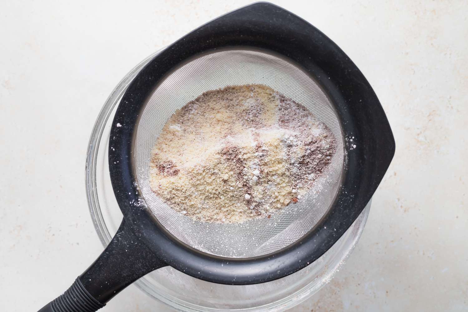 Sifting dry ingredients to make chocolate macarons.
