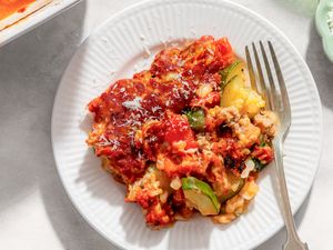 A plate of zucchini pizza bake served with a fork showcasing melted cheese and vegetables in a tomatobased sauce