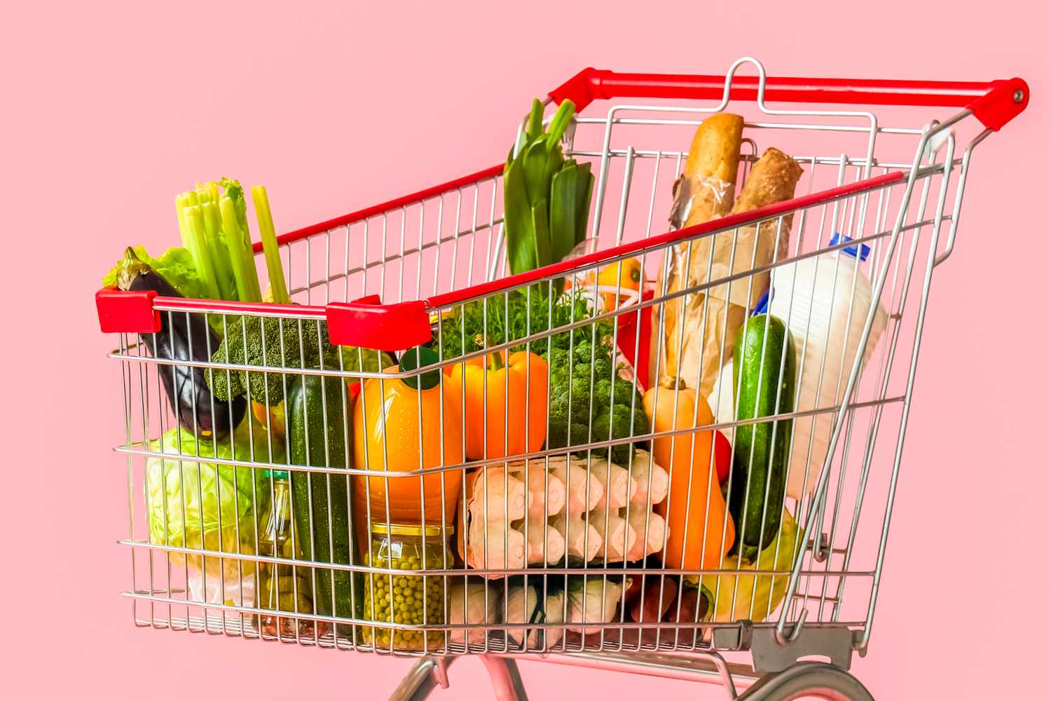 Shopping cart filled with various groceries including fresh vegetables bread and packaged goods
