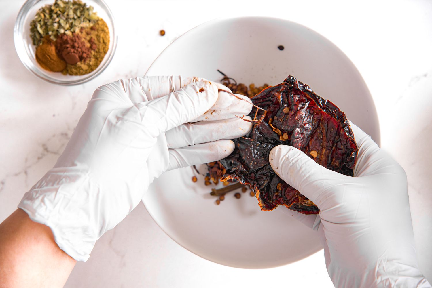 Gloved Hands Removing Seeds from Roasted Peppers for Red Enchilada Sauce Recipe