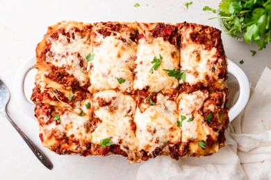 Overhead view of a pan of lasagna cut into squares.