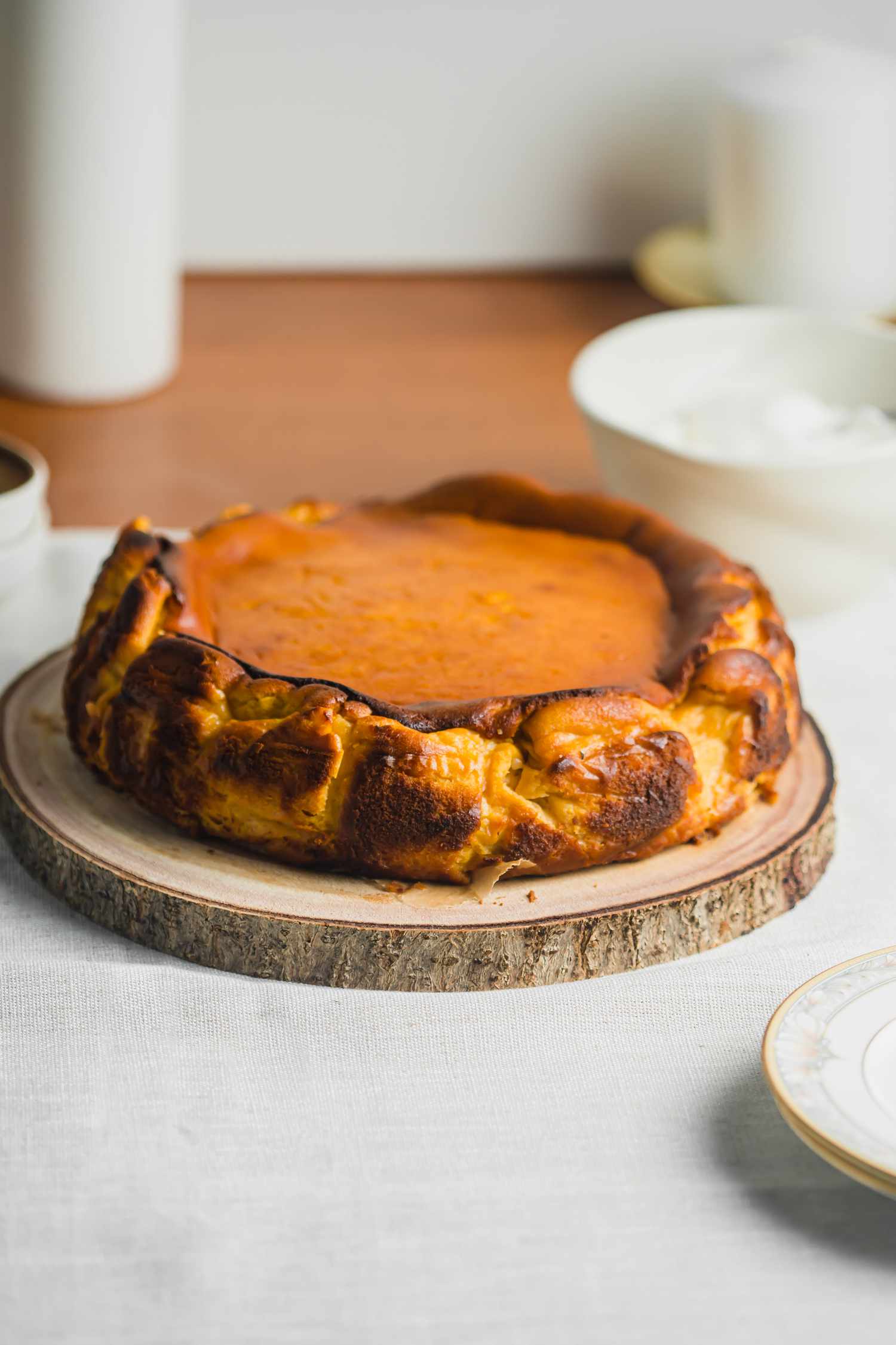Side view of a basque cheesecake on a wooden serving platter.