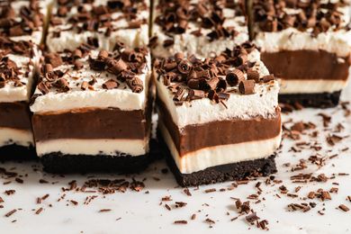 Layered dessert squares with chocolate cream and a cookie base topped with chocolate shavings