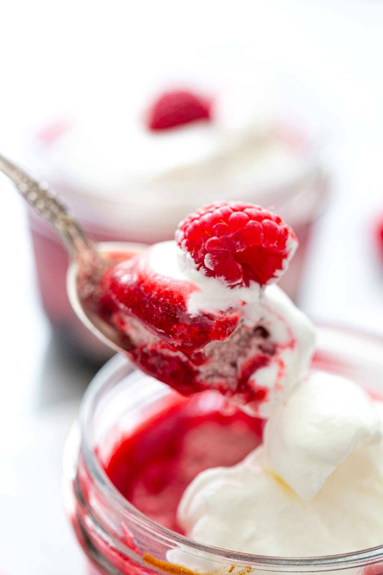 Raspberry cheesecake in a jar with a scoop taken out with a spoon