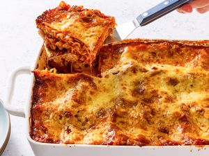 A rectangular dish of homemade lasagna with a portion being served with a spatula