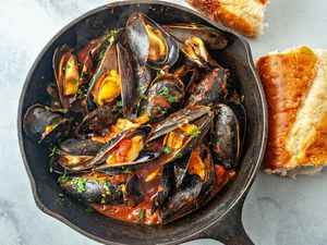 Mussels in tomato sauce recipe - overhead photo of mussels in cast iron pan with bread