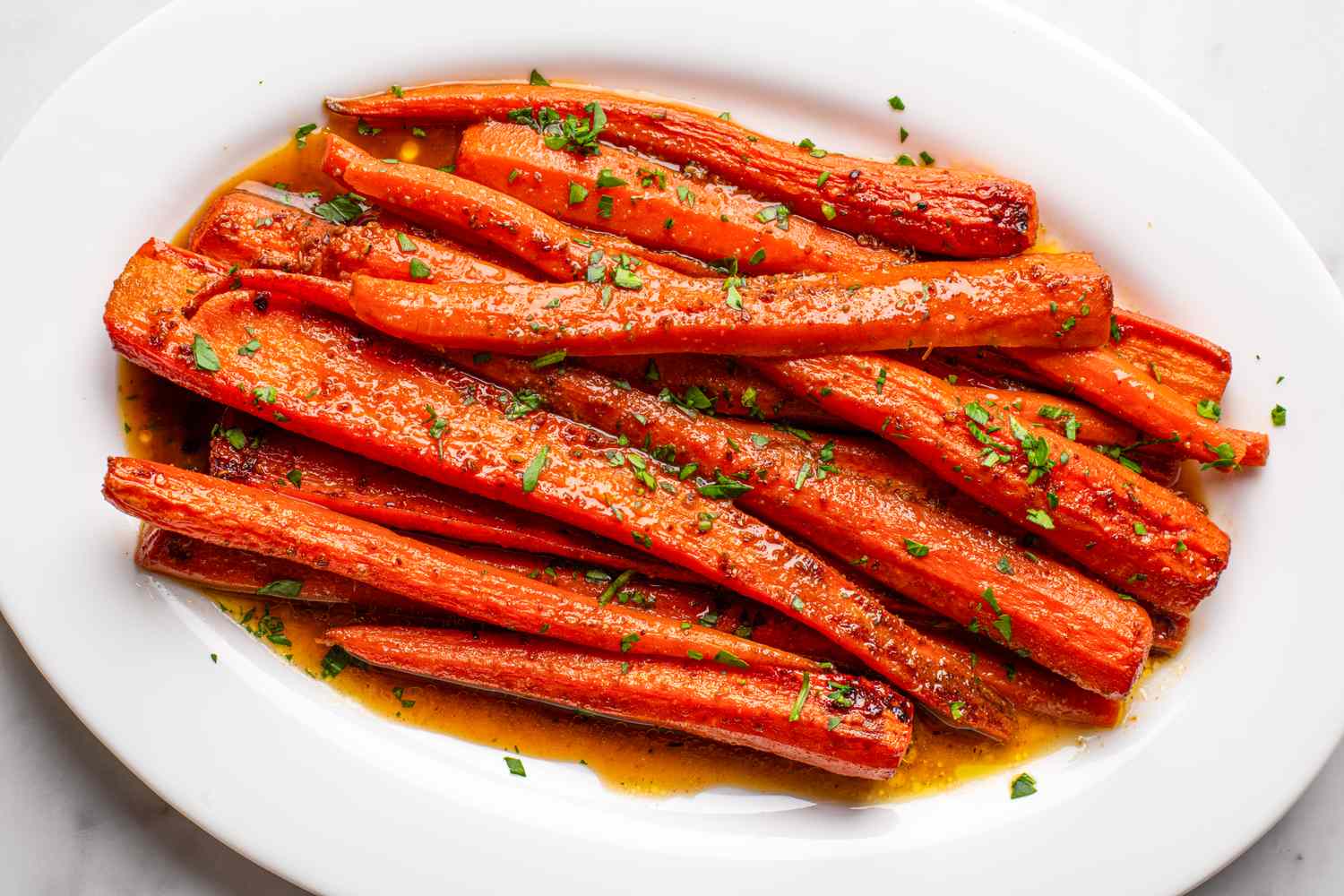 Roasted carrots garnished with herbs on a white plate