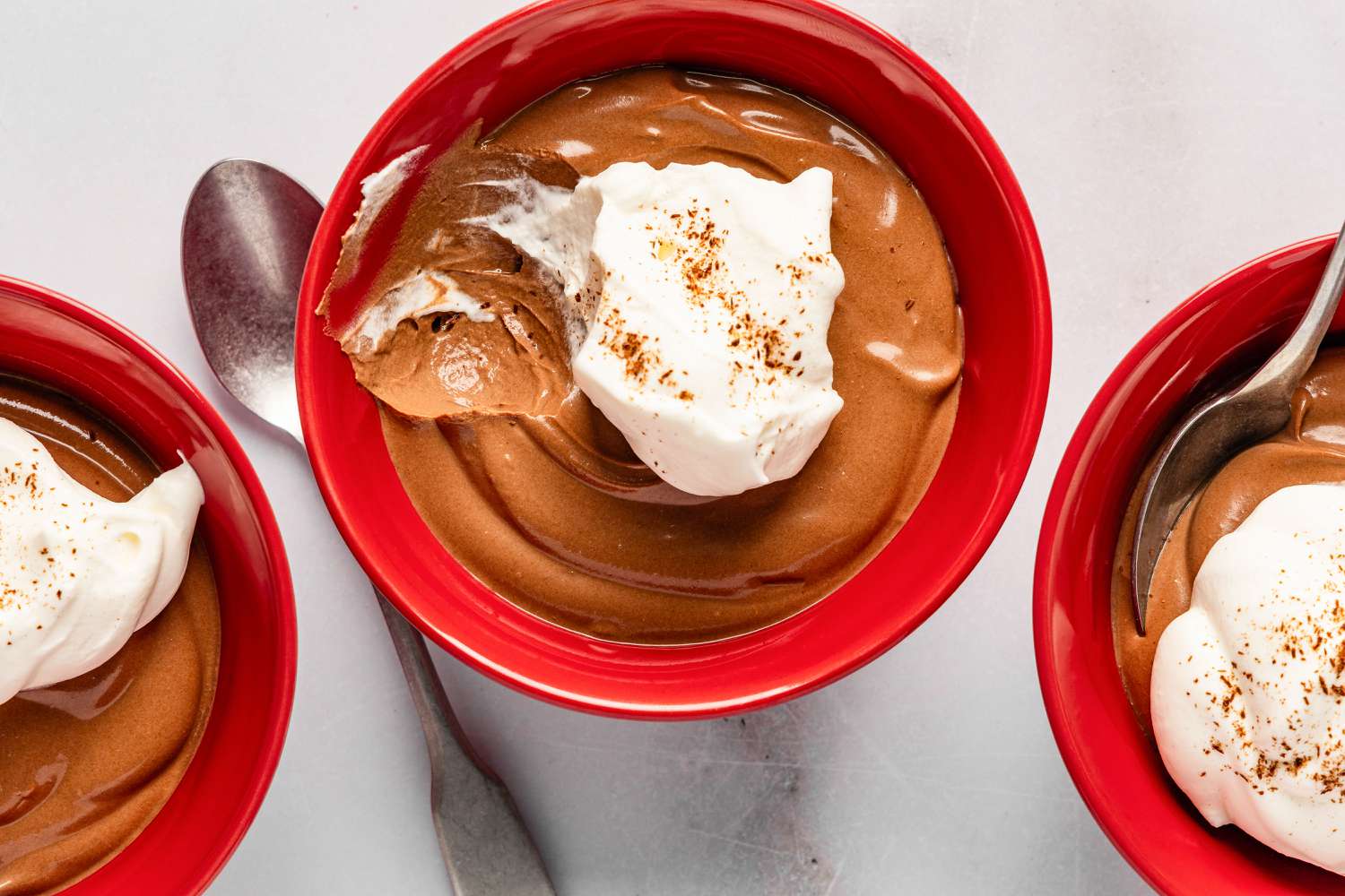 2-Ingredient Chocolate Pudding topped with whipped cream and cocoa powder in bowls with spoons