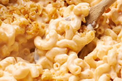Close-up: wooden spoon lifting mac and cheese