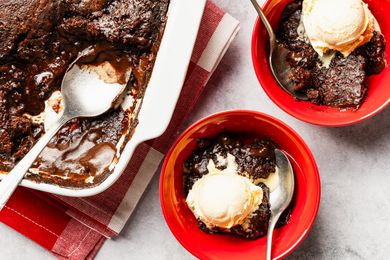 two bowls of chocolate pudding cake with scoops of vanilla ice cream next to a baking pan with more cake