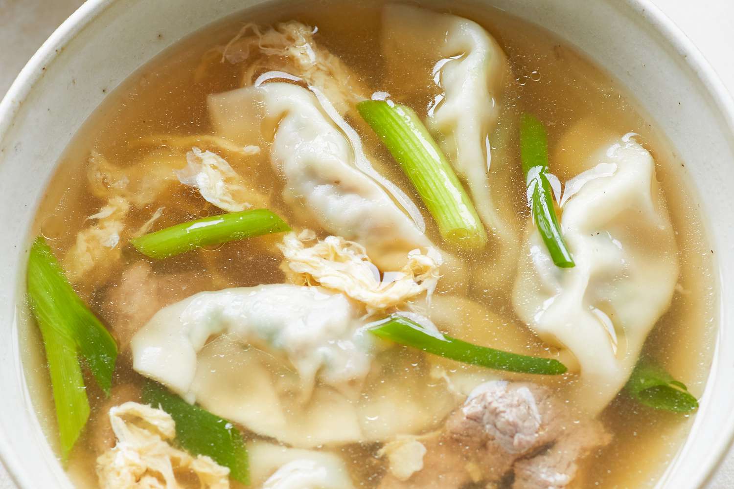 Overhead view of a bowl of beef soup with dumplings.