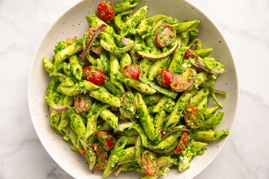 Pasta with cherry tomatoes spinach feta cheese and pesto in a bowl