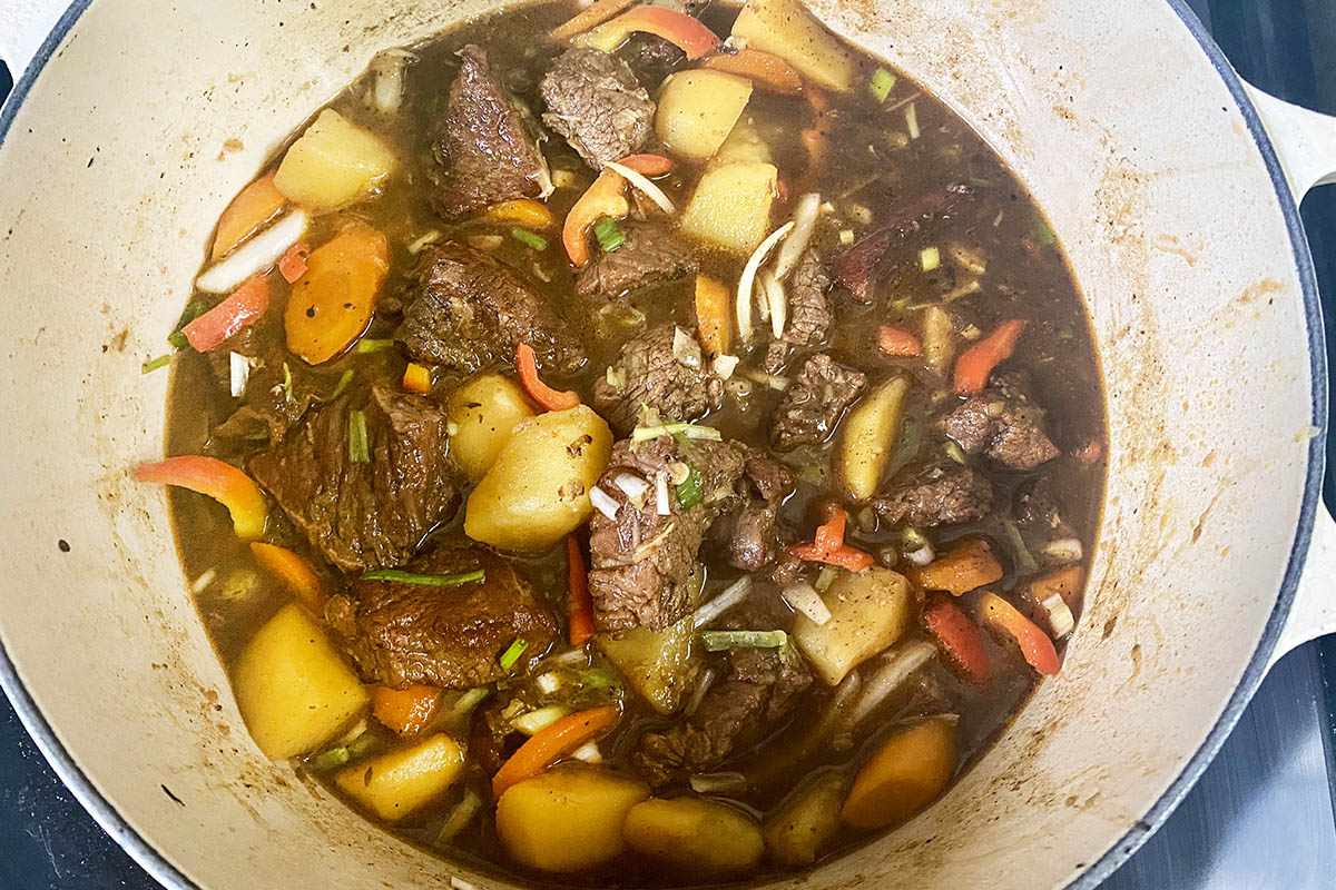 Jamaican Beef Stew cooking in a dutch oven.