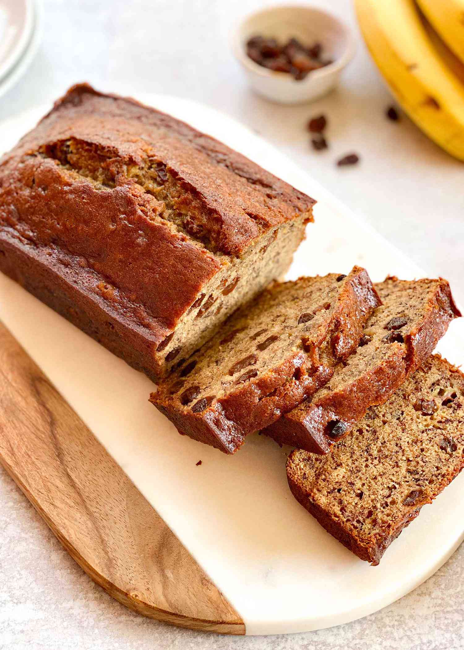 A loaf of rum raisin banana bread with four slices cut off and laying next to each other.