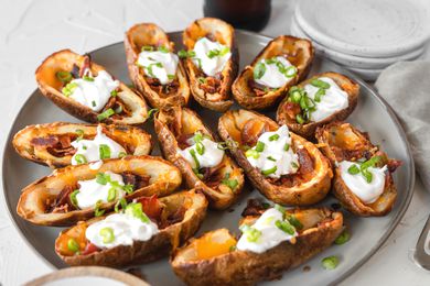 A platter of potato skins topped with cheese and sour cream.
