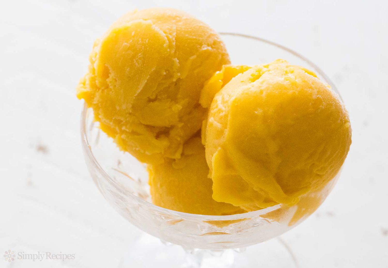 A bowl with three scoops of mango sorbet