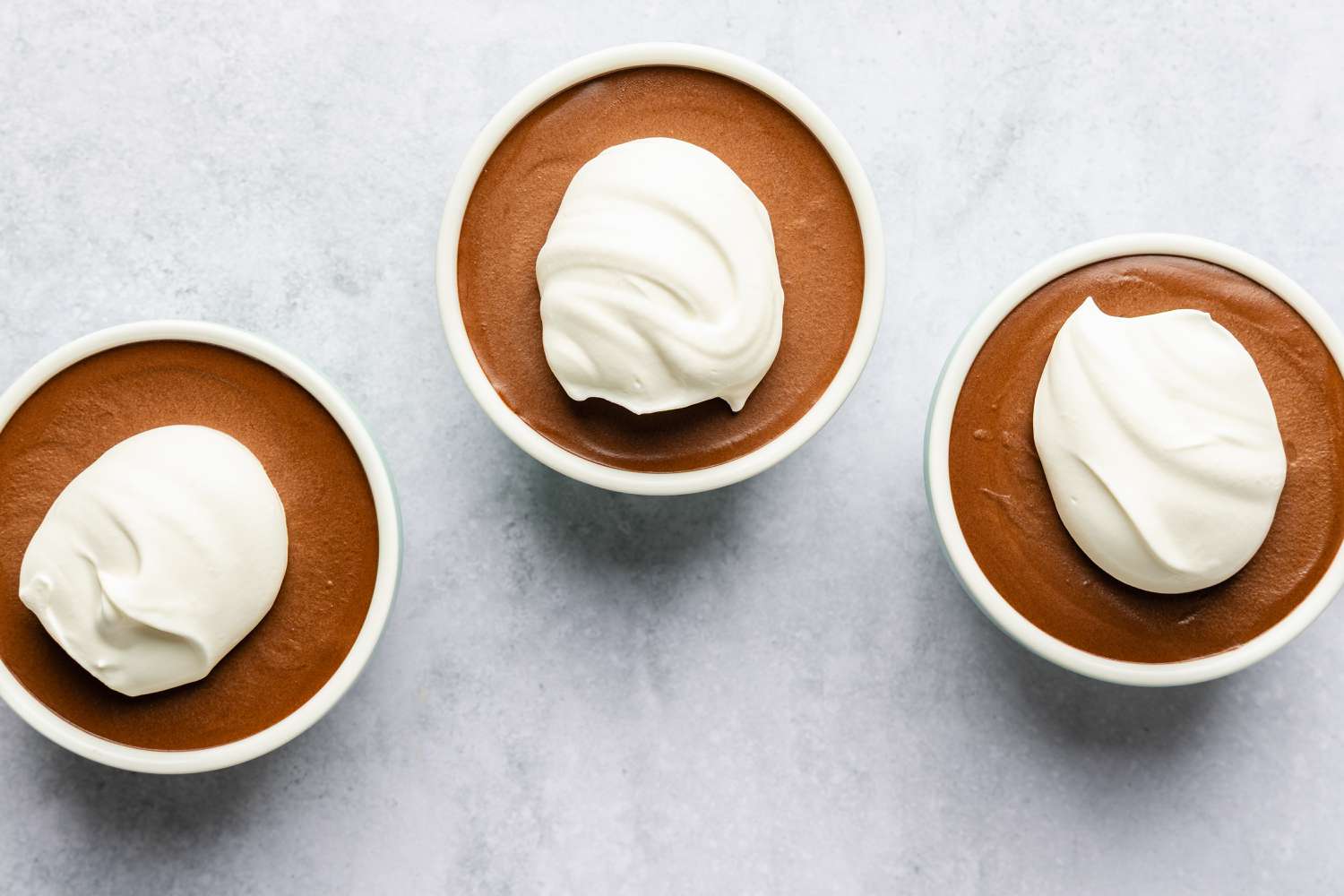 Three ramekins with chocolate mousse and whipped topping