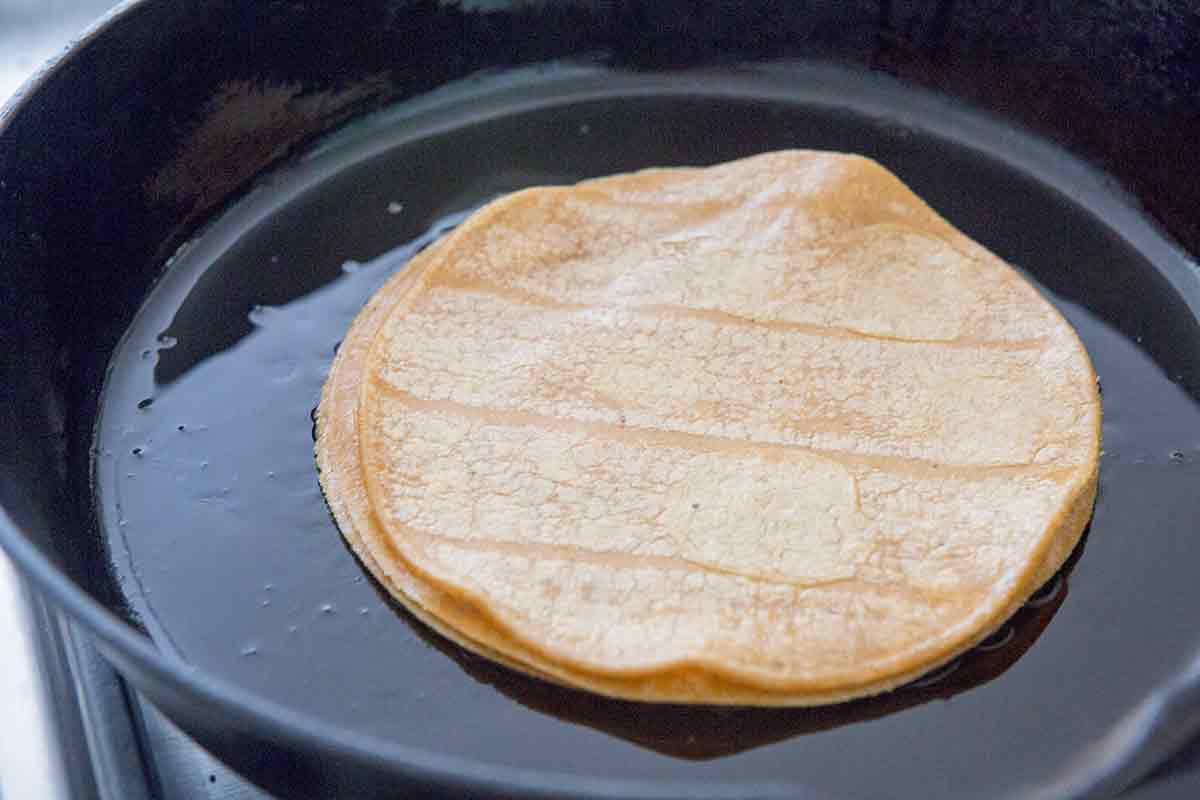 Uncooked Corn Tortillas in a Greased Black Pan 