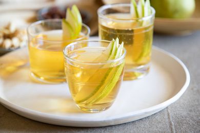 Three glasses of spiced pear bourbon punch on a tray.