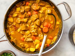 A pot of Japanese curry with vegetables and meat served with white rice on the side