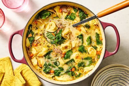 A pot of creamy tortellini soup with spinach and vegetables