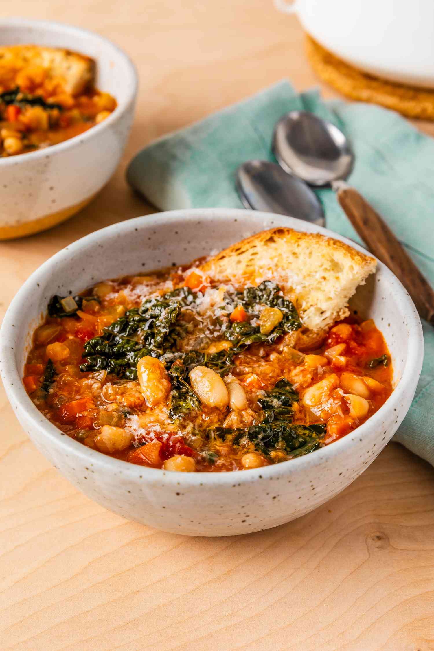 easy tuscan ribolitta soup at a table setting with another bowl, utensils on a table napkin, and a dutch oven