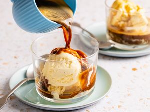 Espresso being poured over ice cream in a glass affogato dessert