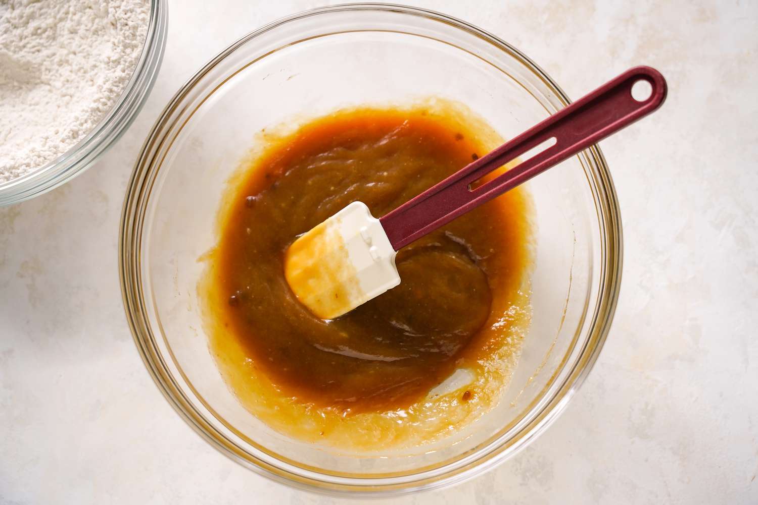 Bowl of Wet Ingredients With a Spatula Next to a Bowl of Dry Ingredients