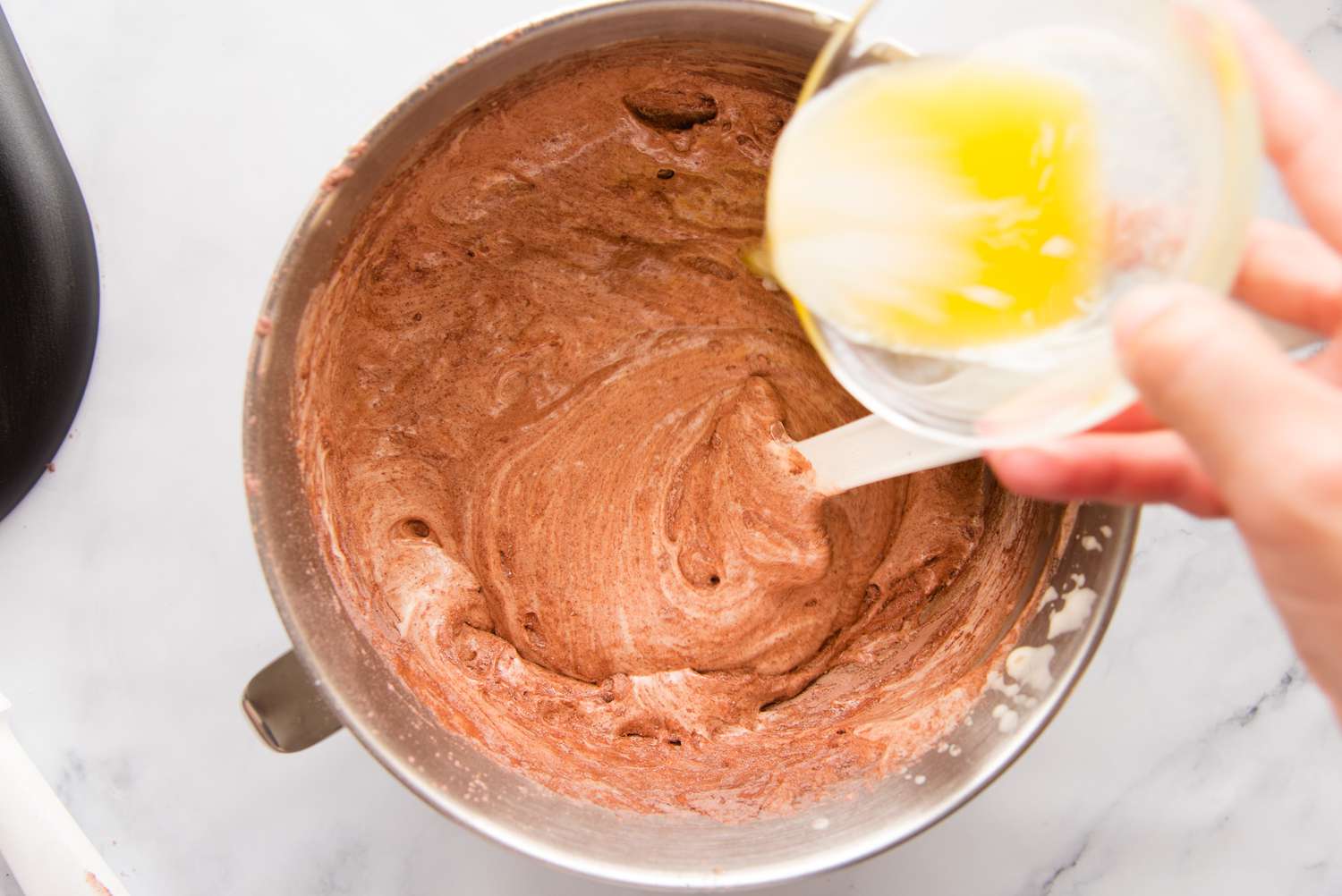 Adding butter to the batter to make a best swiss roll cake recipe.