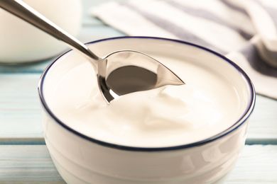 A bowl of yogurt with a metal spoon resting on it