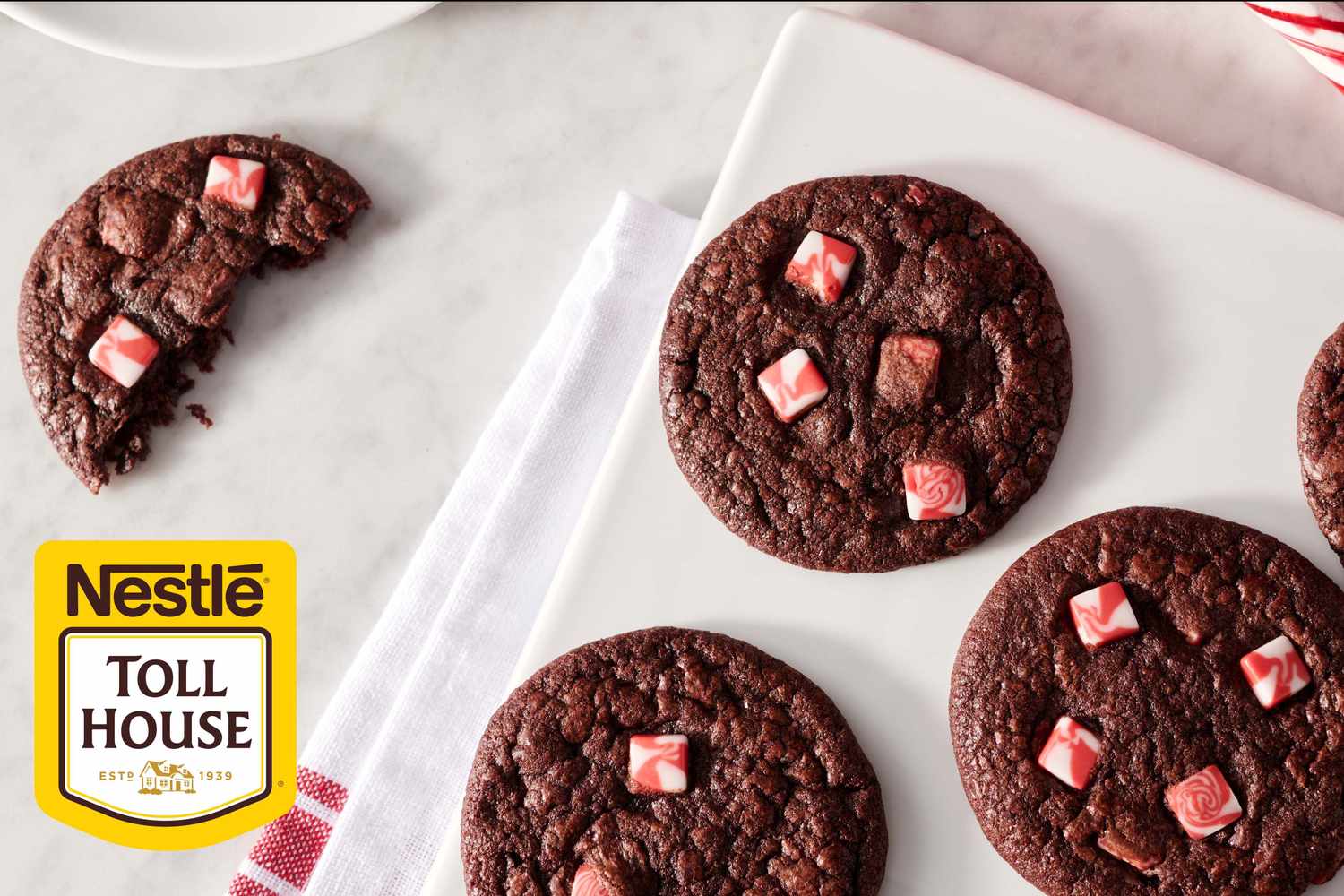 Chocolate cookies with peppermint chunks displayed on a tray next to the Nestle Toll House logo