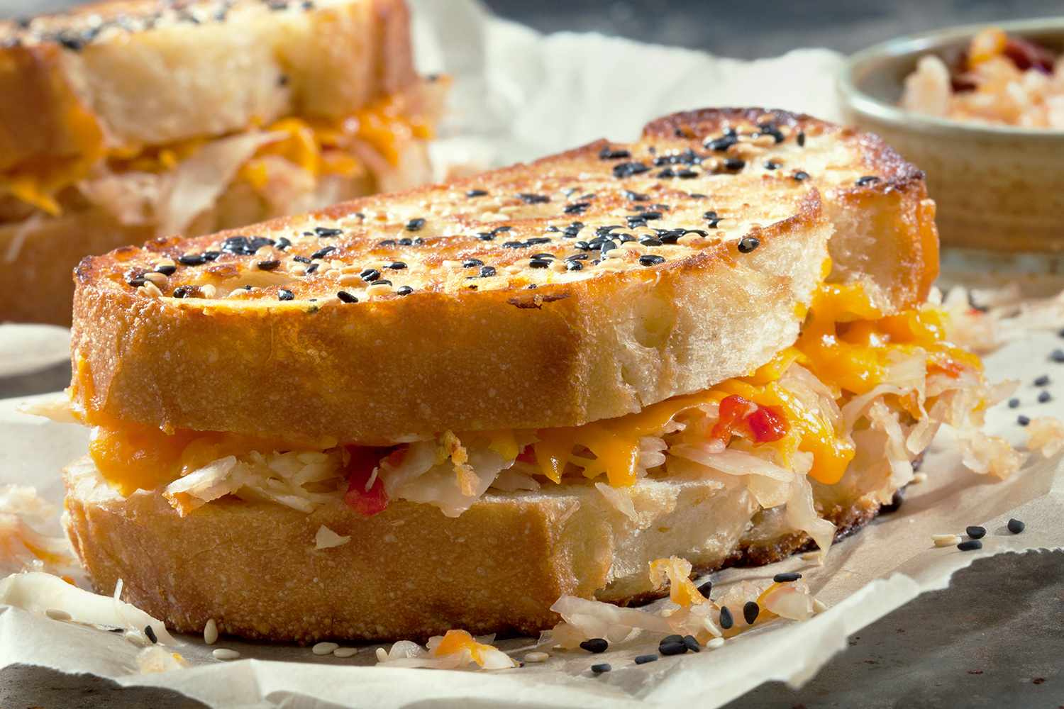 Grilled cheese sandwich filled with kimchi and melted cheese sprinkled with sesame seeds