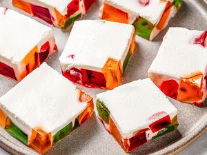 Squares of colorful jello pieces topped with a cream layer on a gray plate