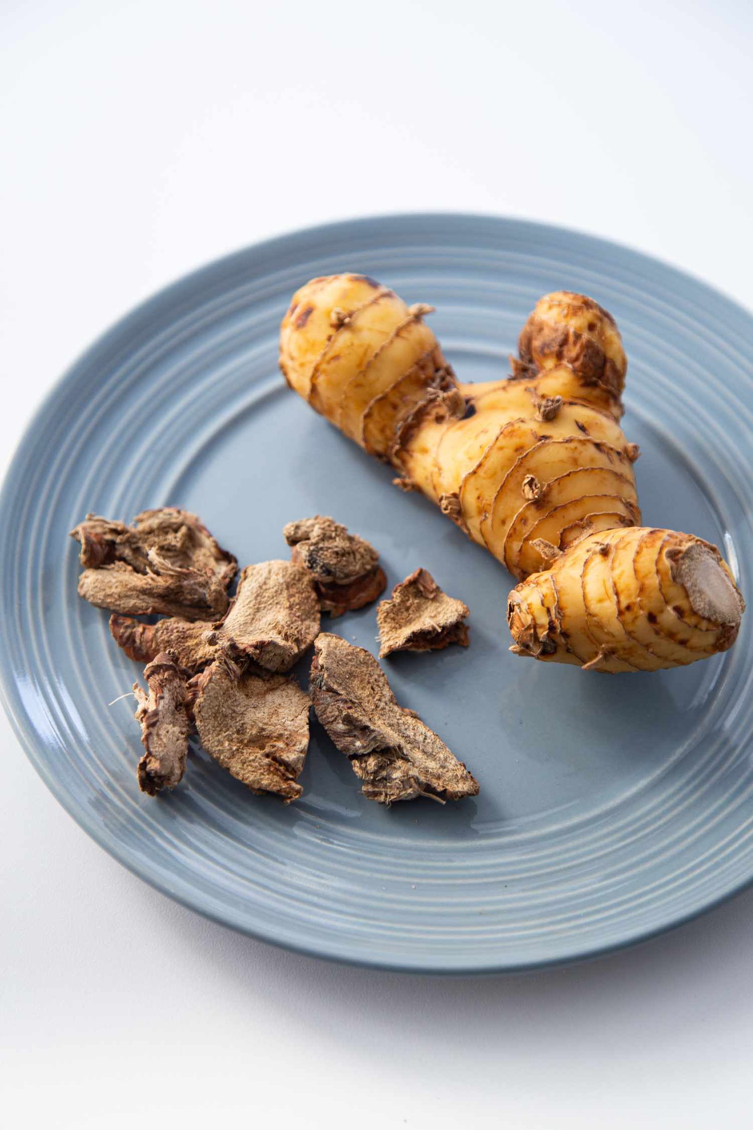 Fresh and dehydrated galangal on a blue plate