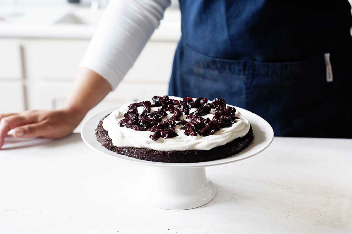 How to make Black Forest Cake by layering a chocolate cake, whipped cream and cherries.
