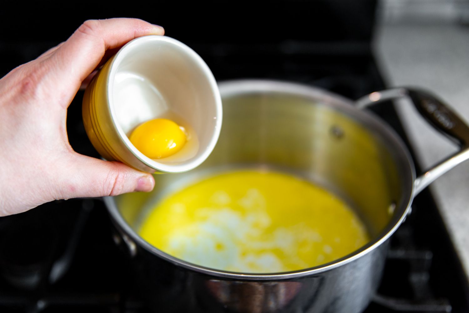 egg being added to pot of wet ingredients for mac and cheese