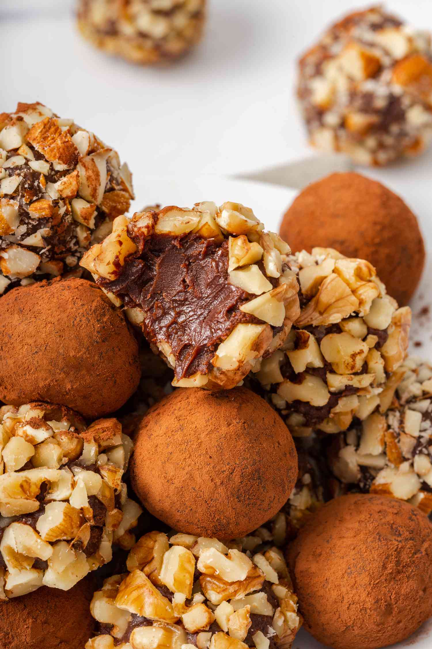 Overhead view of chocolate truffles with the top one with a bite out of it.
