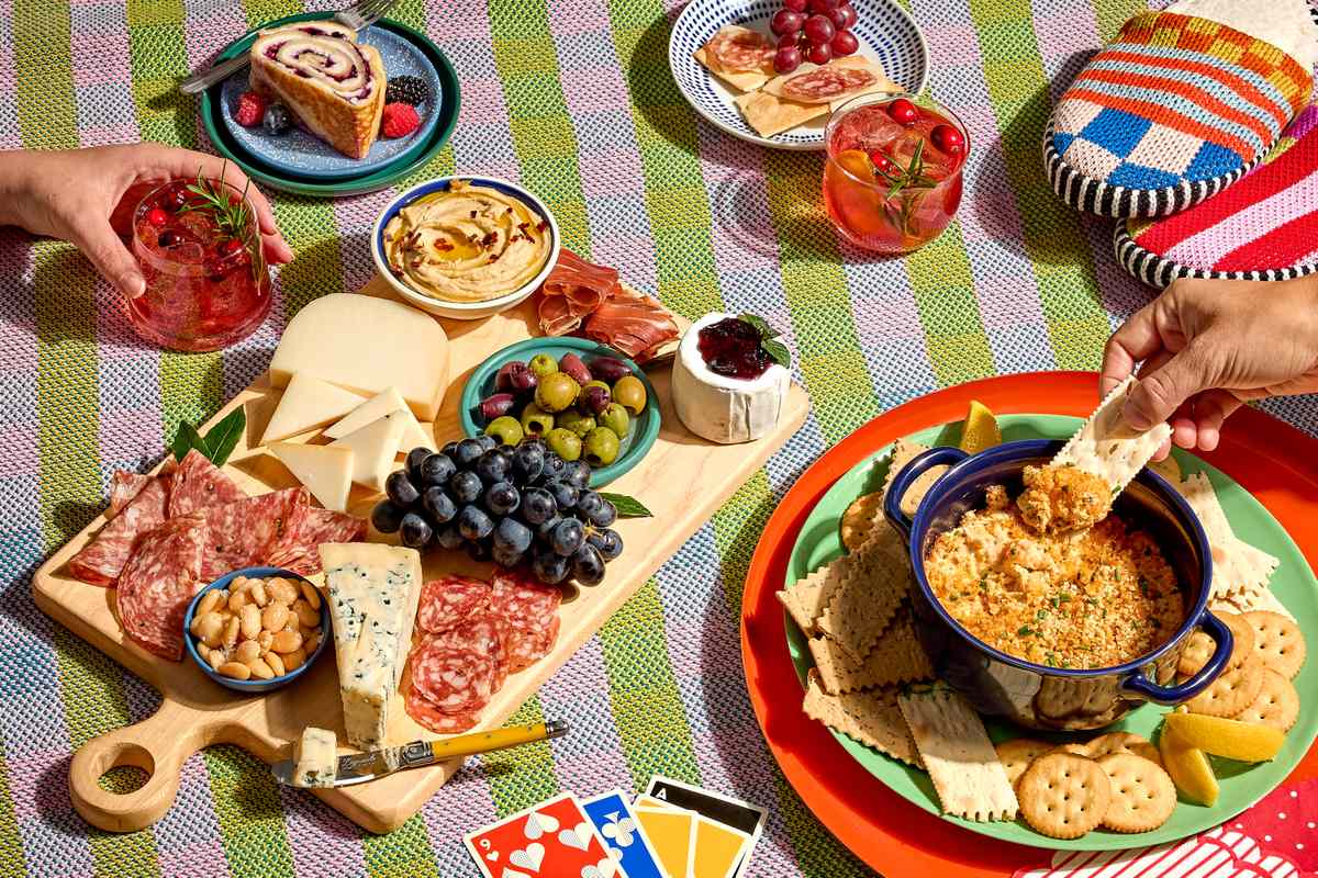 Table setting with charcuterie cheese plates dip and drinks accompanied by a card game
