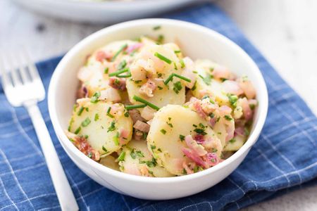 Warm German Potato Salad served in a bowl on a cloth mat with a fork