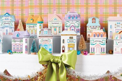 Miniature village houses themed as spice containers arranged festively on a display with holiday decorations