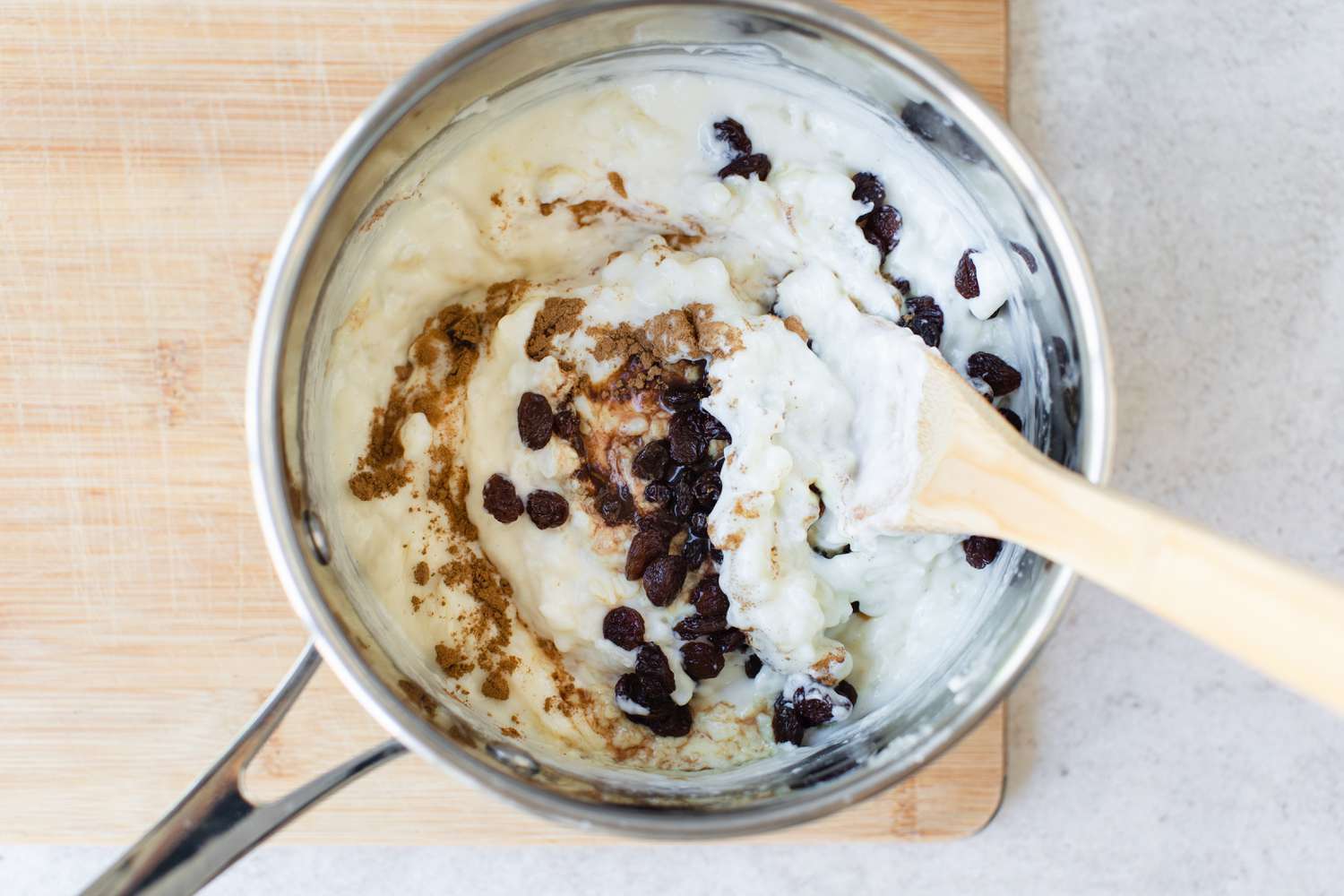 Stirring raisins and vanilla into a saucepan of Rice Pudding