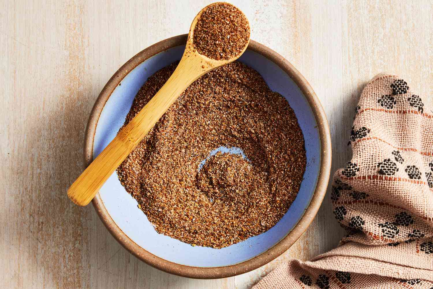 Bowl of Fajita Seasoning With Some in a Spoon Resting on the Bowl, and on the Counter, a Kitchen Towel