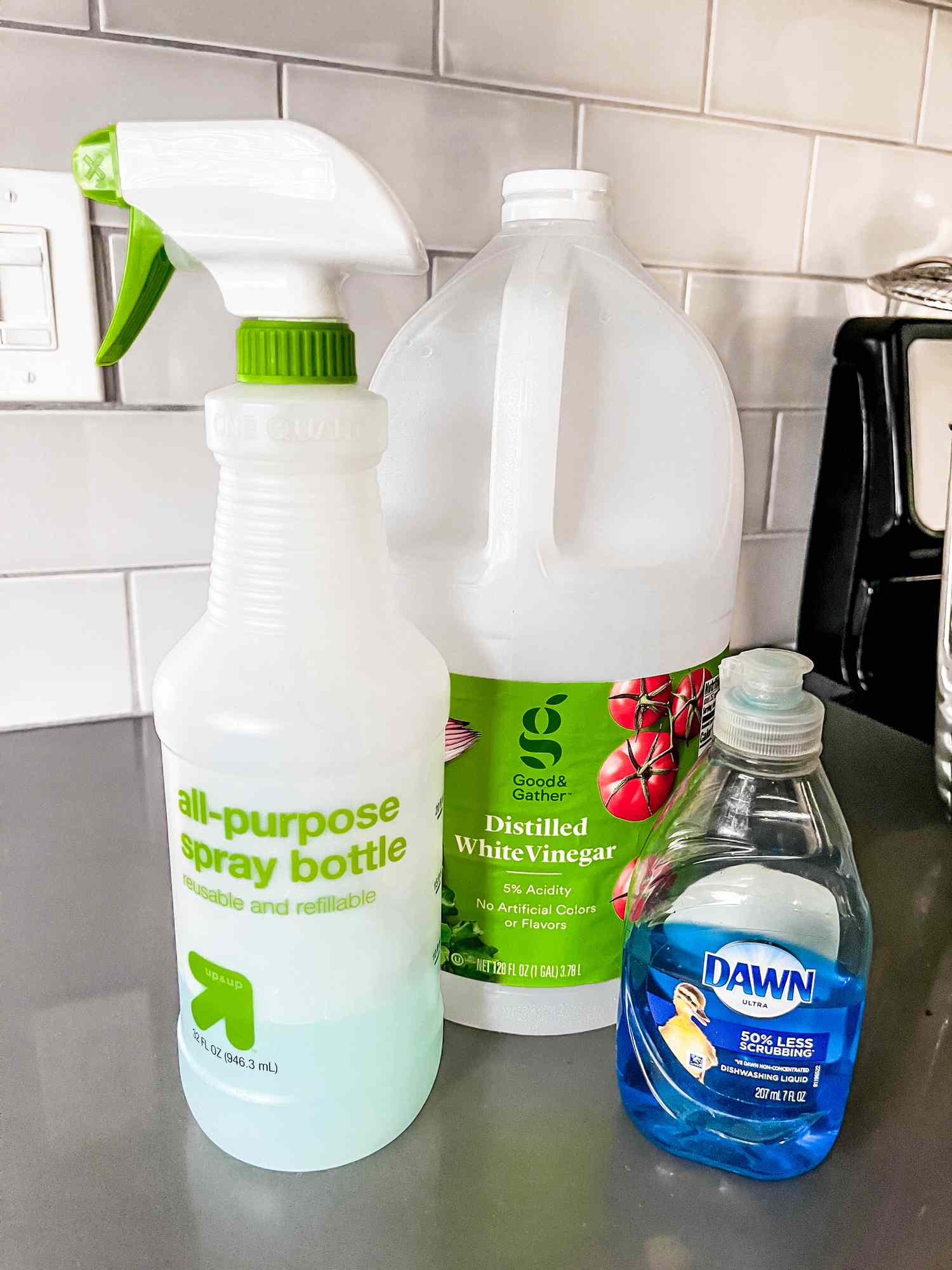 All-purpose spray bottle, a jug of distilled white vinegar, and Dawn soap on a counter