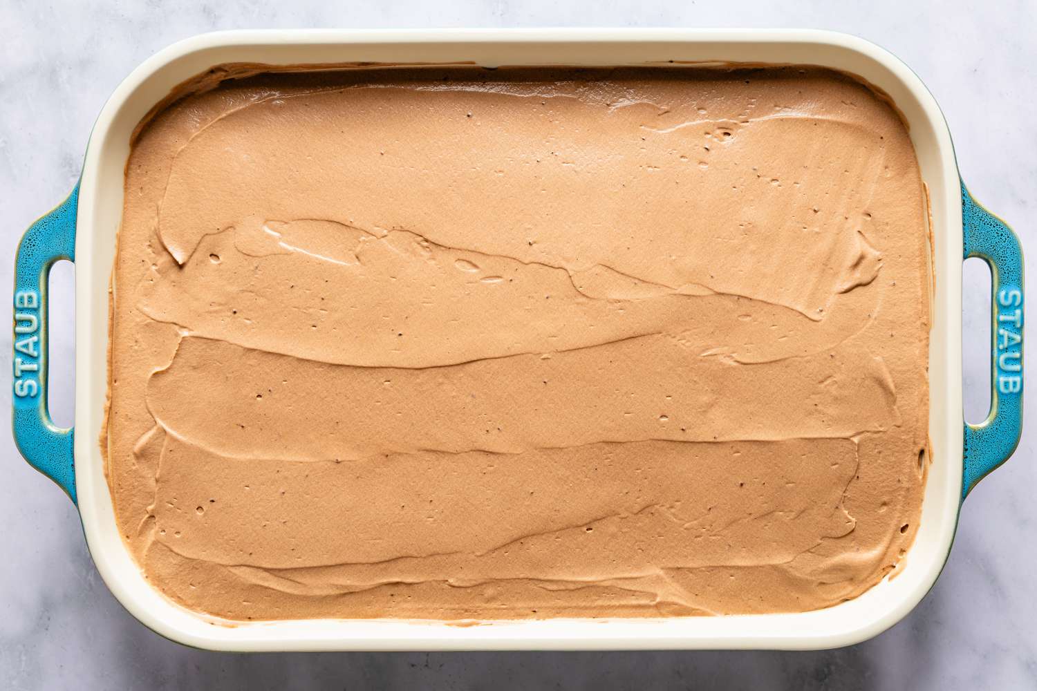 The top chocolate cream smoothly layered on top of the baked Italian love cake in rectangular pan, ready for serving